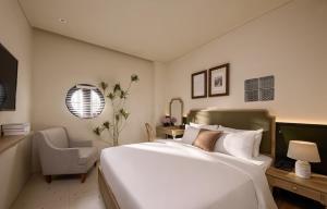a bedroom with a large white bed and a chair at LoverA Signature Hotel in Ho Chi Minh City