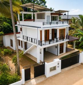 a white house with a fence and a palm tree at Ivy Garden Retreat in Gampola