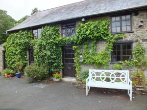ランダバリーにあるThe Byreの石造りの家の前の白いベンチ