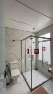 a bathroom with a toilet and a glass shower at Recanto Pau Brasil in Sete Lagoas