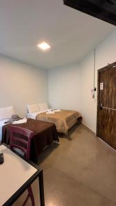 a room with two beds and a table and a door at Recanto Pau Brasil in Sete Lagoas