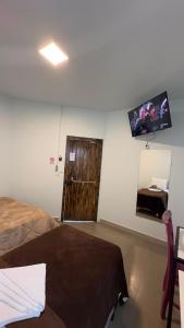 a bedroom with a bed and a door with a television at Recanto Pau Brasil in Sete Lagoas