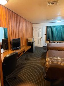 a hotel room with two beds and a desk and a television at Motel Garberville in Garberville