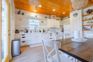 a kitchen with white cabinets and a wooden ceiling at Salty Waves | Beach Cottage, Walk to Beach, Pool, Fenced Yard & Grill in Port Aransas +26 photos