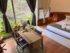 a bedroom with a bed and a desk and a table at The ForRest Peace Forest แม่กำปอง in Ban Huai Kaeo
