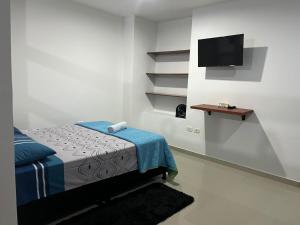 a bedroom with a bed and a flat screen tv at Tayra Living Suites in Mocoa