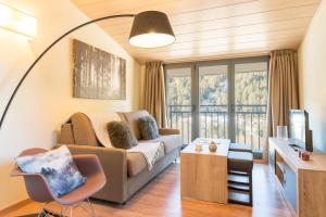 een woonkamer met een bank en een groot raam bij Pierre & Vacances Andorra Sunari Peretol in Bordes d´Envalira 