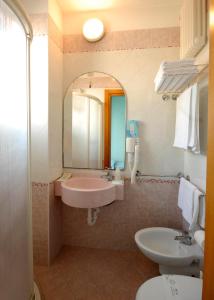 uma casa de banho com um lavatório, um WC e um espelho. em Hotel Christian em Rimini