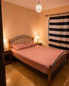a bedroom with a large bed with two tables and a window at Résidence Tarifa in Mrarech
