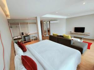 a bedroom with a large white bed and a couch at Platinum hotel in Rayong