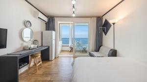 a bedroom with a bed and a desk and a refrigerator at Yangyang Verit Pension in Yangyang
