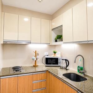 a kitchen with white cabinets and a microwave at The Mactan Beach Condo Staycation in Punta Engaño