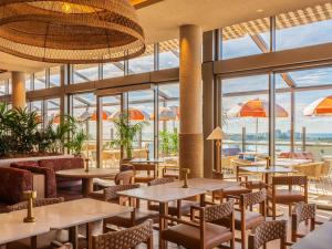 a restaurant with tables and chairs and windows at Avani Mooloolaba Beach Hotel in Mooloolaba