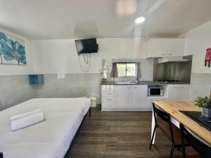 a small white kitchen with a bed and a table at Young Tourist Park in Young