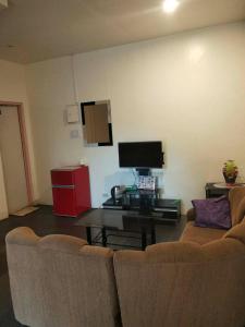 a living room with a couch and a table and a tv at Janisah Pension House in Narra