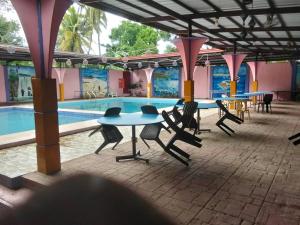 a pool with tables and chairs next to a swimming pool at Janisah Pension House in Narra