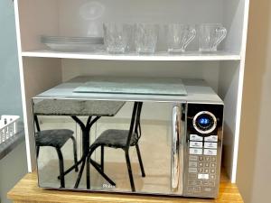 a microwave oven with two stools inside of it at Garagem, Pátio Privativo - Apartamento Completo Moderno in Campo Novo do Parecis
