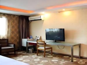 a hotel room with a desk with a television on the wall at Juntong Hotel in Bao'an