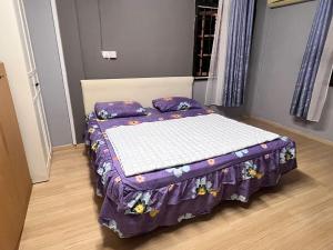 a bed with a purple comforter in a room at Harmoni Group Stay in Bintulu