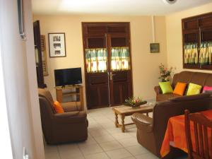 a living room with two couches and a tv at Cap soleil in Sainte-Anne