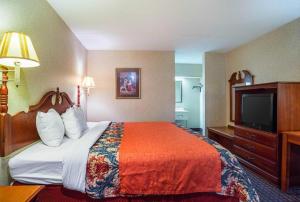 a hotel room with a bed and a flat screen tv at Rodeway Inn & Suites in Tupelo