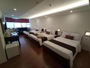 a hotel room with two beds and a couch at Hotel Asuncion in Laoag