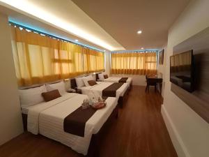 a hotel room with three beds and a television at Hotel Asuncion in Laoag