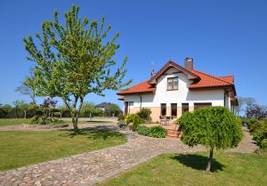 una casa blanca con techo rojo y dos árboles en Villa Cis, en Darłowo