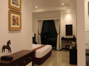 a hotel room with a bedroom with a bed and a desk at Baan Nan Hotel in Nan