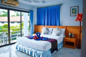 a bedroom with a large bed with blue curtains at Pailin Hotel Krabi in Klong Muang Beach