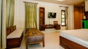 a bedroom with a bed and a desk and a television at Tong Hotel in Ban Nong Chik