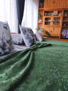 a green blanket laying on top of a bed at Родопско сърце in Chepelare