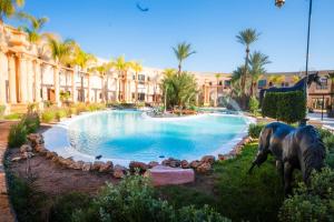 a swimming pool with a statue in front of a building at Rose Garden Resort & Spa in Marrakesh