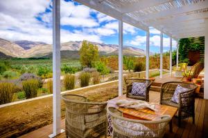 porche con mesa y sillas y vistas a las montañas en Vrisch Gewagt Boutique Self-Catering Olive Farm, en Prince Albert