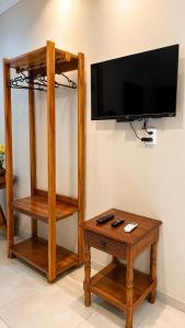 a living room with a tv on a wall with a table at Pousada Coco Babaçu in Viçosa do Ceará