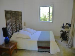 ein weißes Schlafzimmer mit einem Bett und einem Fenster in der Unterkunft L'Ostal du Pic St Loup in Saint-Jean-de-Cuculles