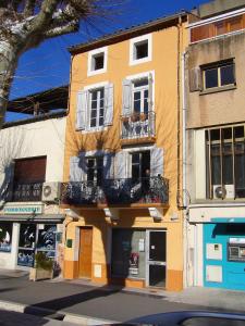 a yellow building with a balcony on a street at Nidélice Chambre d'hôtes in Quillan
