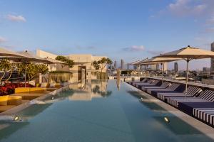 a hotel swimming pool with lounge chairs and umbrellas at Dizengoff 99 by Isrotel Design in Tel Aviv