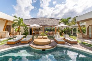 an outdoor swimming pool with lounge chairs and a villa at SUMA Bali in Uluwatu