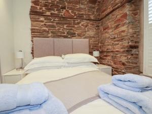 a bedroom with two beds and a brick wall at Rock House in Tintagel