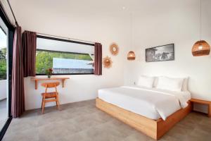 a bedroom with a bed and a desk and a window at Villa Panoramic in Nusa Penida