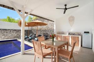 a kitchen and dining room with a table and an umbrella at Villa Panoramic in Nusa Penida