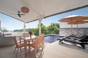 a patio with a table and chairs and a pool at Villa Panoramic in Nusa Penida