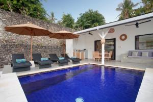 a pool with chairs and umbrellas next to a house at Villa Panoramic in Nusa Penida