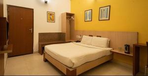 a bedroom with a bed and a yellow wall at Sparrow Hotels Alwar, Sariska in Alwar