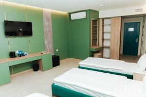 a room with two beds and a desk and a tv at Leore Hotel in Namangan