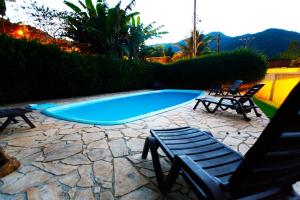 a swimming pool with two chairs and a bench at Chales Maresias in Maresias