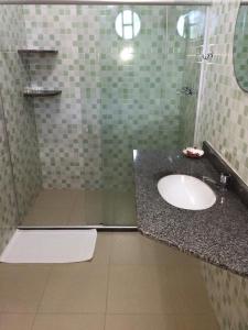 a bathroom with a sink and a glass shower at Pousada Nascente Pequena in Guapimirim