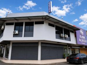 a white building with a car parked in front at HM SweetRest HOTEL in Changlun