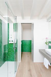 a bathroom with green tiles and a glass shower at Casa Burano in Burano